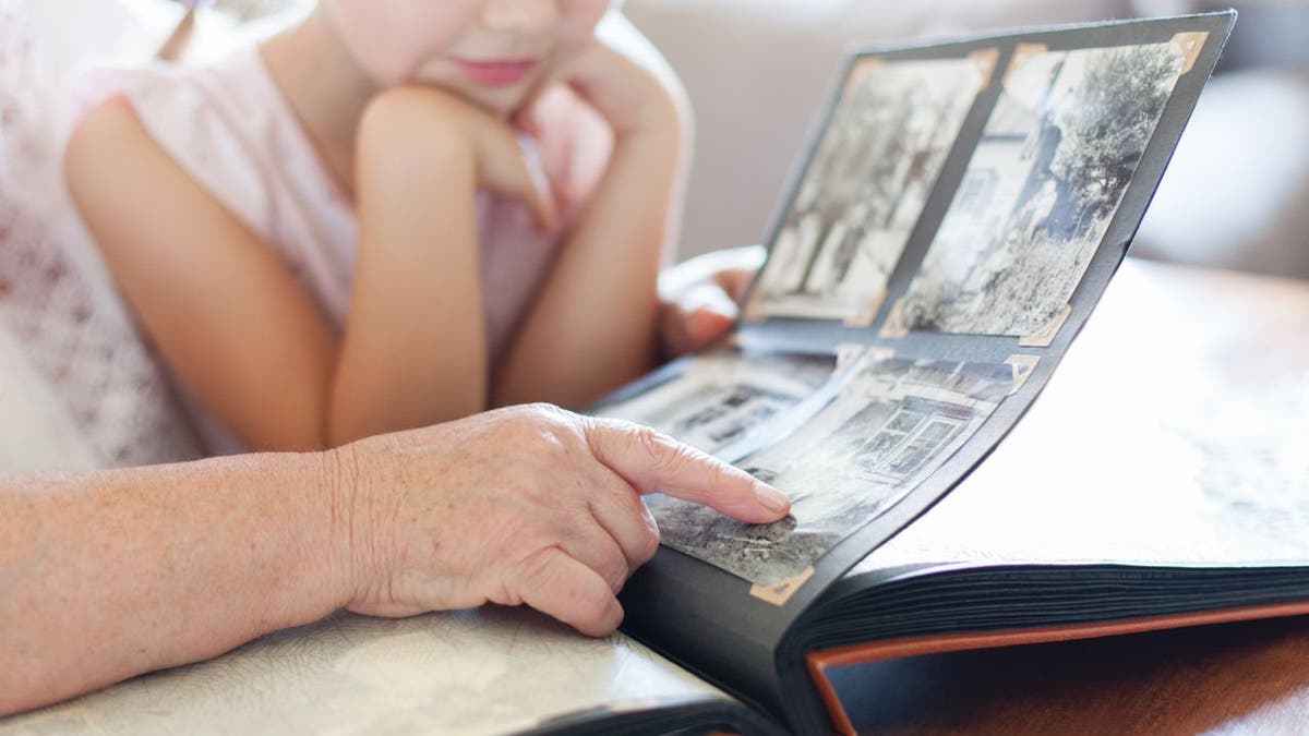 Child looks at photo album with an adult