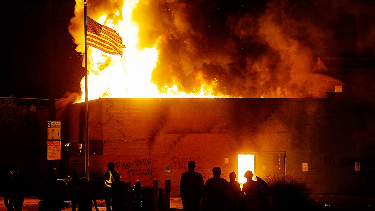 Photo showing riot in Kenosha with fire raging behind American flag