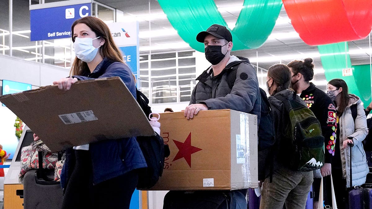 FILE - Travelers line up wearing protective masks indoors at O'Hare International Airport in Chicago, Dec. 28, 2021. (AP Photo/Nam Y. Huh, File)