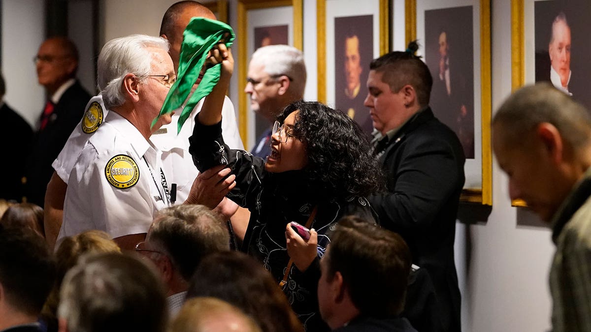 An unidentified pro-choice protester is removed by security as she heckles U.S. Supreme Court Associate Justice Amy Coney Barrett as she meets with Board of Trustees Chairman Frederick J. Ryan, Jr., at the Ronald Reagan Presidential Library Foundation in Simi Valley, Calif., Monday, April 4, 2022. (AP Photo/Damian Dovarganes)