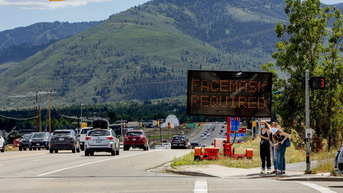 Pedestrians walk in front of a street sign that reads "Face Mask Requried" in Summit County near Park City, Utah, U.S., on Saturday, Aug. 1, 2020.  Photographer: Kim Raff/Bloomberg via Getty Images