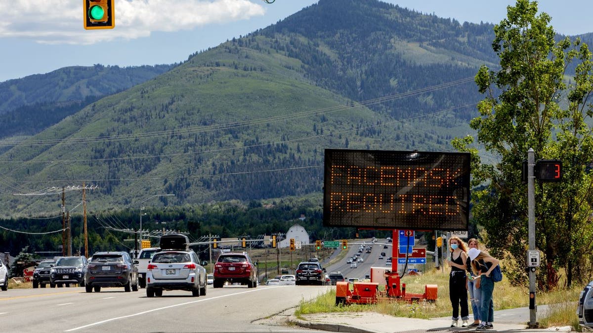 Pedestrians walk in front of a street sign that reads "Face Mask Requried" in Summit County near Park City, Utah, U.S., on Saturday, Aug. 1, 2020. Photographer: Kim Raff/Bloomberg via Getty Images