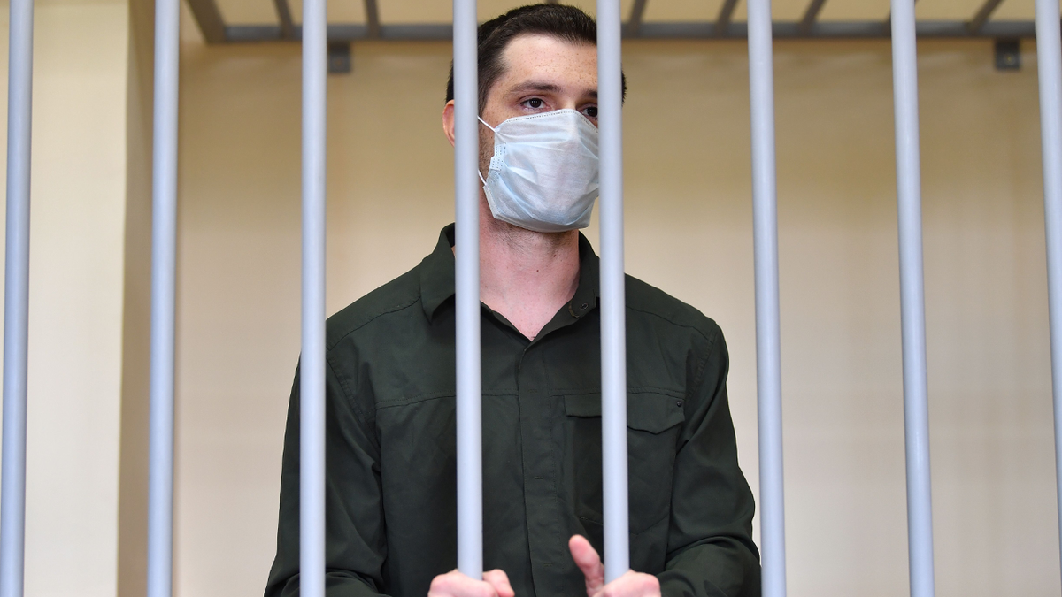 Trevor Reed waring face mask behind bars