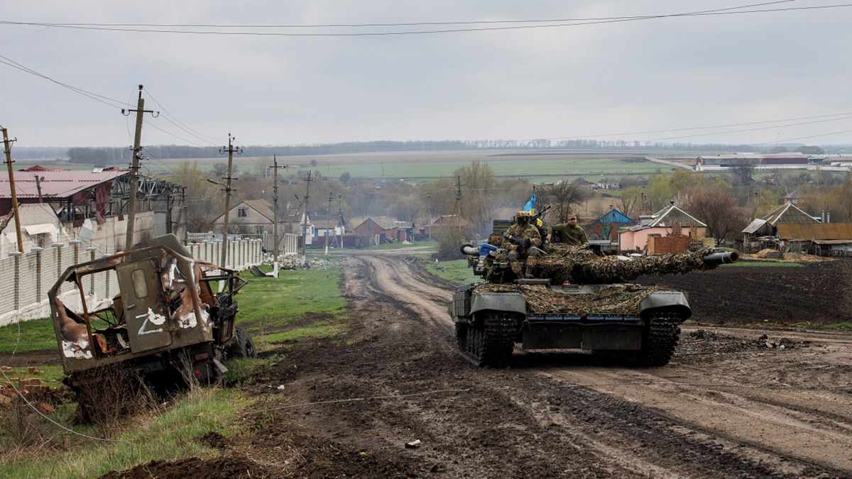 A Ukrainian tank drives next to a destroyed Russian vehicle in the Kharkiv region on April 14.