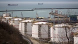 Oil storage tanks stand at the RN-Tuapsinsky refinery, operated by Rosneft Oil Co., as tankers sail beyond in Tuapse, Russia, on Monday, March 23, 2020.