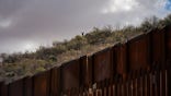 SASABE, ARIZONA - JANUARY 23: Migrants wait on the Mexican side for the U.S. Border Patrol agents to leave the border wall between the U.S. and Mexico to cross to an area where the wall is not complete near the city of Sasabe, Arizona, Sunday, January 23, 2022.