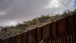 Migrants wait on the Mexican side for the U.S. Border Patrol agents to leave the border wall between the U.S. and Mexico to cross to an area where the wall is not complete near the city of Sasabe, Arizona