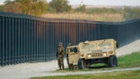 FILE: National Guardsmen stands watch over a fence near the International bridge where thousands of Haitian migrants have created a makeshift camp, on Sept. 18, 2021, in Del Rio, Texas.