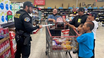 Police officers hand out cash to help pay for families' groceries in California