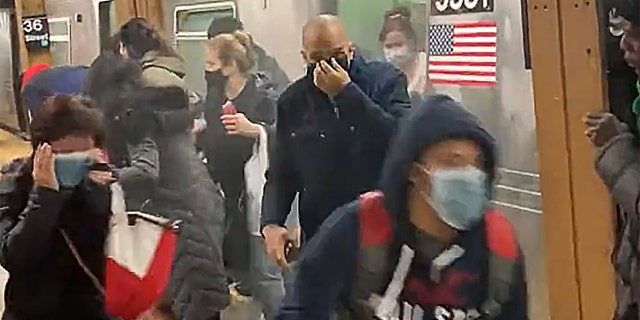 In this photo from social media video, passengers run from a subway car in a station in the Brooklyn borough of New York, Tuesday, April 12, 2022.