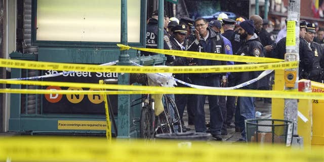 New York City Police Department personnel gather at the entrance to a subway stop in Brooklyn on April 12, 2022.