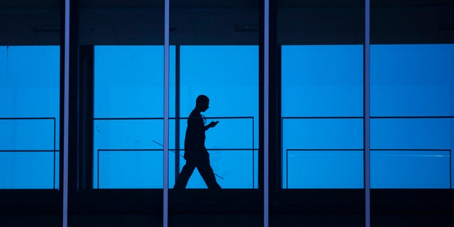 A student uses his mobile phone as he walks inside the Engineering building at the University of Waterloo.