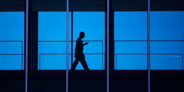 A student uses his mobile phone as he walks inside the Engineering building at the University of Waterloo.