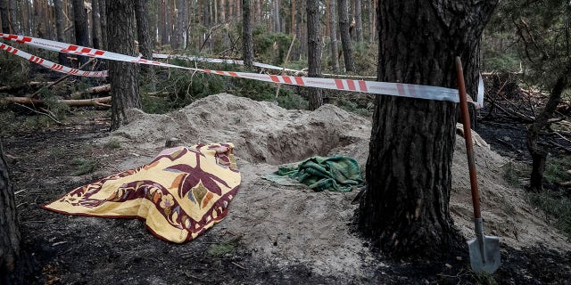 The body of civilian woman Yaroslava 43, is covered with a blanket near a grave, according to residents Yaraslova was killed by Russian soldiers, amid Russia's invasion of Ukraine, in the village of Motyzhyn, in the Kyiv region, Ukraine, April 4, 2022.