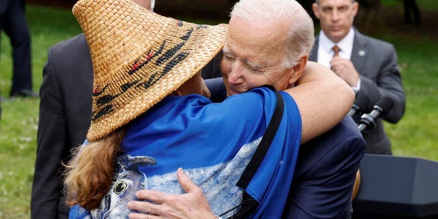 U.S. President Joe Biden embraces Tulalip Tribes Chairwoman Teri Gobin, who wears a traditional Native American hat, as he gives her the pen he used to sign an executive order intended as an initiative to conserve old-growth forests in federal lands, after delivering remarks about climate change and protecting national forests on Earth Day, at Seward Park in Seattle, Washington, U.S. April 22, 2022.