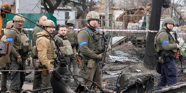Ukrainian President Volodymyr Zelenskyy, center left, examines the site of a recent battle in Bucha, close to Kyiv, Ukraine, Monday, April 4, 2022.