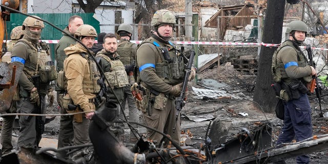 Ukrainian President Volodymyr Zelenskyy, center left, examines the site of a recent battle in Bucha, close to Kyiv, Ukraine, Monday, Apr. 4, 2022.