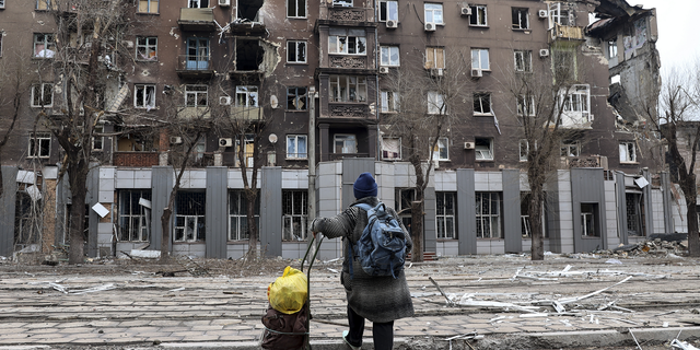 A resident looks at a damaged apartment building in Mariupol, Ukraine, on Saturday. 