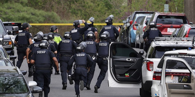 Metropolitan Police sprint up Van Ness Street Northwest toward the scene of the shooting on April 22, 2022, in Washington, DC. 