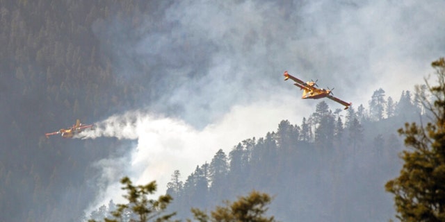 In this photo released by the U.S. Forest Service, aircraft known as "super scoopers" battle the Hermits Peak and Calf Canyon Fires in the Santa Fe National Forest in New Mexico on Tuesday, April 26, 2022. Firefighters have been making significant progress on the biggest wildfires burning unusually hot and fast for this time of year in the western U.S. But forecasters from the Southwest to the southern High Plains are warning of the return the next two days of the same gusty winds and critical fire conditions that sent wildland blazes racing across the landscape last week. 