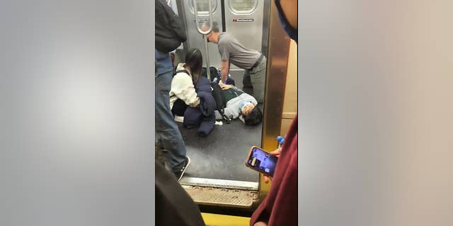 This photo provided by Will B Wylde, a person is aided in a subway car in the Brooklyn borough of New York, martedì, aprile 12, 2022.