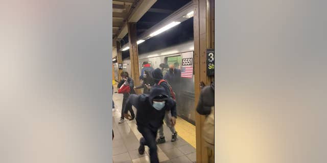 In this photo from social media video, passengers run from a subway car in a station in the Brooklyn borough of New York, Tuesday, April 12, 2022.