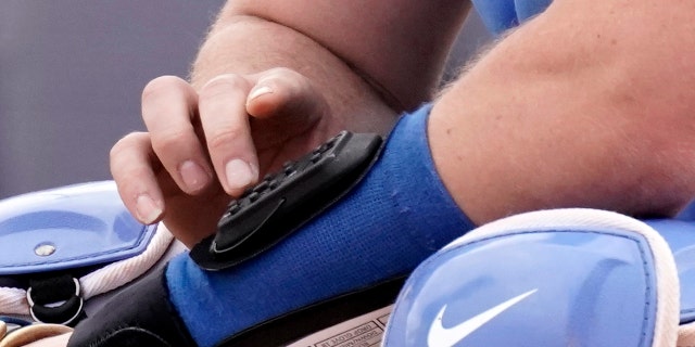 MLB looking at electronic system for calling pitches Kansas City Royals catcher Cam Gallagher uses a wrist-worn device used to call pitches during the sixth inning of a spring training game against the Seattle Mariners March 29, 2022, in Peoria, Ariz.