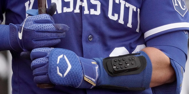 MLB looking at electronic system for calling pitches Kansas City Royals catcher Cam Gallagher wears a wrist-worn device used to call pitches as he prepares to bat during the sixth inning of a spring training game against the Seattle Mariners March 29, 2022, in Peoria, Ariz.