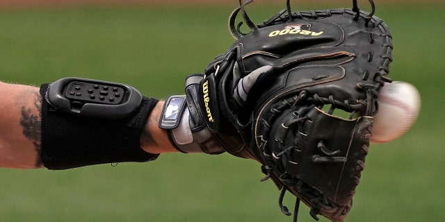MLB looking at electronic system for calling pitches Seattle Mariners catcher Tom Murphy wears a wrist-worn device used to call pitches as he catches a ball during the sixth inning of a spring training game against the Kansas City Royals March 29, 2022, in Peoria, Ariz.