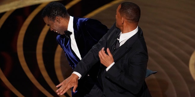 Will Smith hits presenter Chris Rock on stage while Rock presents the award for best documentary feature at the Oscars.