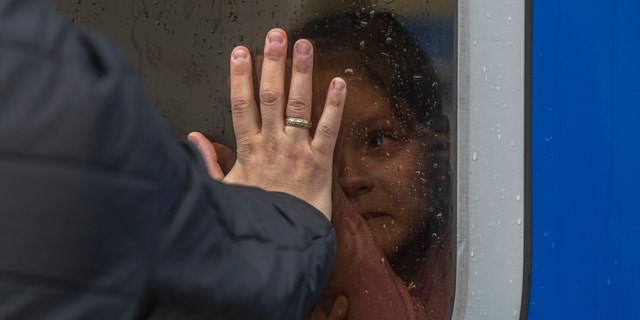 A girl inside a train reacts as she says goodbye to relatives at the train station in Odesa, before she and members of her family escape the war in Ukraine to Poland, on Saturday, April 2, 2022. 