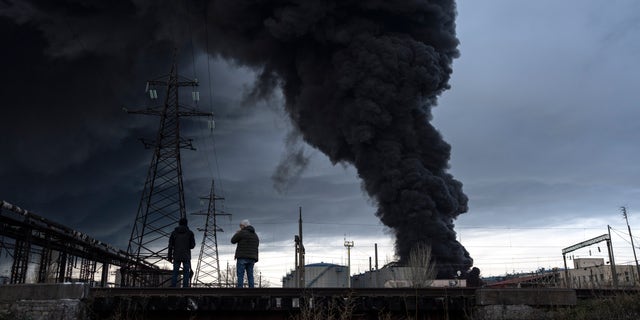 Les gens regardent la fumée monter dans l'air après le bombardement d'Odessa, en Ukraine, le dimanche 3 avril 2022. 