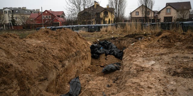 The bodies lie in a mass grave in Bucha on the outskirts of Kiev, Ukraine on Sunday, April 3, 2022. Ukrainian troops are finding brutalized bodies and widespread destruction on the outskirts of Kiev, sparking new demands for a war crimes investigation and sanctions against Russia.