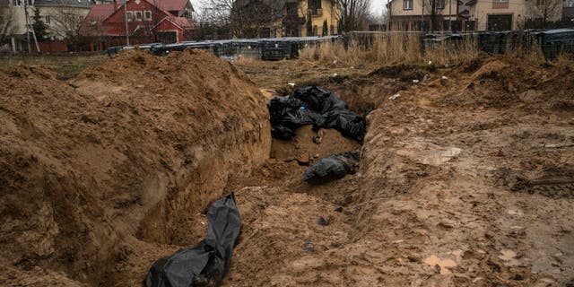 Bodies lie in a mass grave in Bucha, on the outskirts of Kyiv, Ukraine, Sunday, April 3, 2022. Ukrainian troops are finding brutalized bodies and widespread destruction in the suburbs of Kyiv, sparking new calls for a war crimes investigation and sanctions against Russia.