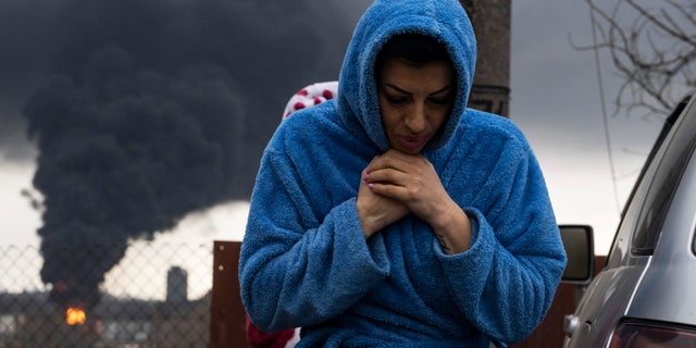 A woman walks as smoke rises in the air in the background after shelling in Odesa, Ukraine, Sunday, April 3, 2022.