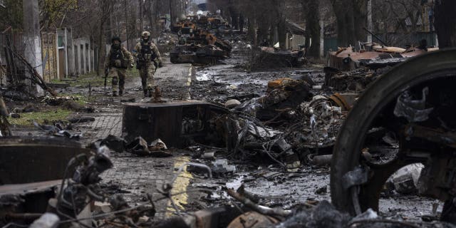 Soldiers walk amid destroyed Russian tanks in Bucha, on the outskirts of Kyiv, Ukraine, Sunday, April 3, 2022.