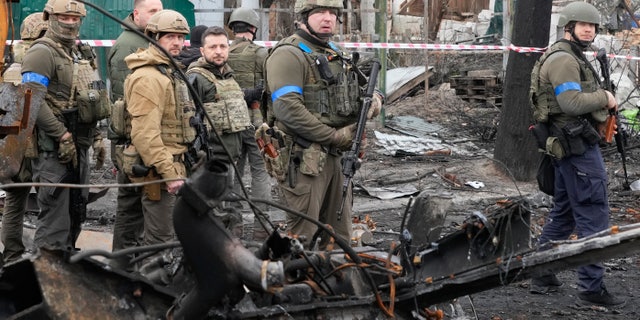 Ukrainian President Volodymyr Zelenskyy, center left, examines the site of a recent battle in Bucha, close to Kyiv, Ukraine, Monday, April 4, 2022.