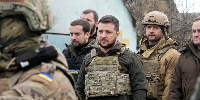 Ukrainian President Volodymyr Zelenskyy examines the site of a recent battle in Bucha on Monday.