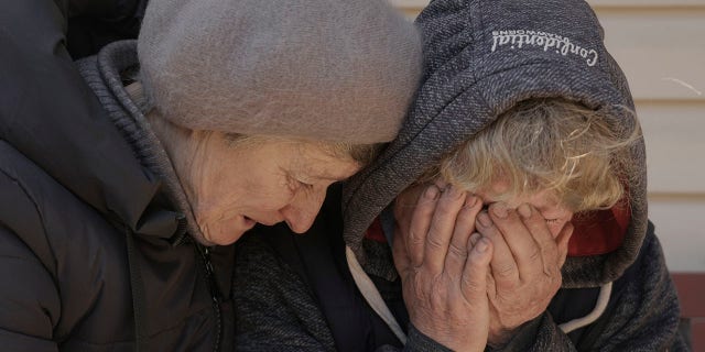 A neighbor comforts Natalya, whose husband and nephew were killed by Russian forces, as she cries in her garden in Bucha, Ukraine, April 4, 2022.