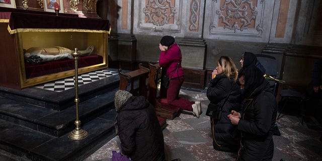 The wife, center, of 44-year-old soldier Tereshko Volodymyr, second right, prays and mourns his death before his funeral ceremony, after he died in action, at the Holy Apostles Peter and Paul Church in Lviv, western Ukraine, Monday, April 4, 2022. (AP Photo/Nariman El-Mofty)