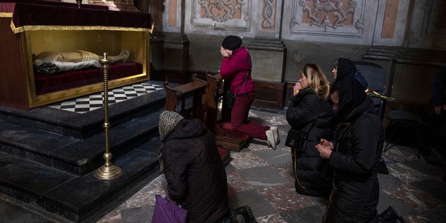 The wife, center, of 44-year-old soldier Tereshko Volodymyr, second right, prays and mourns his death before his funeral ceremony, after he died in action, at the Holy Apostles Peter and Paul Church in Lviv, western Ukraine, Monday, April 4, 2022. (AP Photo/Nariman El-Mofty)