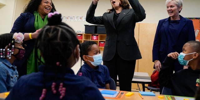 Vice President Kamala Harris, center, standing with Thomas Elementary School principal Jaimee Trahan, left, and Energy Secretary Jennifer Granholm, right, talks with the students during a visit to Thomas Elementary School in Washington, Monday, April 4, 2022. During her visit, Harris announced plans to upgrade public schools with clean energy efficient facilities and transportation. (AP Photo/Susan Walsh)