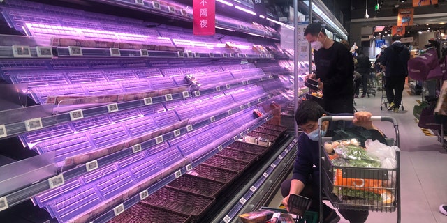 Customers look through empty shelves at a supermarket in Shanghai, China, on March 30, 2022. 