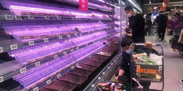 Customers look through empty shelves at a supermarket in Shanghai, China, on March 30, 2022. 