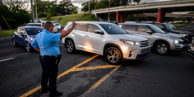 A police officer directs cars along R.H. Tood Avenue after a crash near an intersection during a blackout in San Juan, Puerto Rico, early Thursday, April 7, 2022.