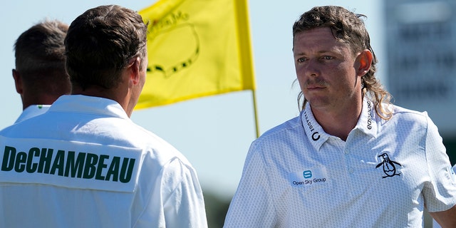 Cameron Smith of Australia (right) shakes hands with Bryson DeChambeau's caddie Brian Zeigler on the 18th green during the first round at The Masters golf tournament on Thursday, April 7, 2022, in Augusta, Georgia. 