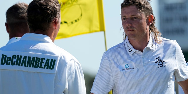 Cameron Smith of Australia (right) shakes hands with Bryson DeChambeau's caddy Brian Zeigler on the 18th green during the first round at The Masters golf tournament on Thursday, April 7, 2022, in Augusta, Georgia.
