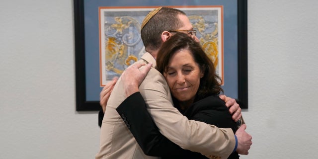 Rabbi Charlie Cytron-Walker, left, gets a hug from Anna Salton Eisen at Congregation Beth Israel in Colleyville, Texas, Thursday, April 7, 2022.