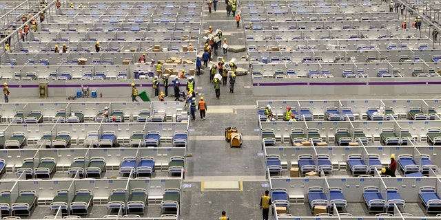 In this photo released by Xinhua News Agency, workers work at the site of a makeshift hospital under construction at the National Exhibition and Convention Center (Shanghai) in eastern China's Shanghai, Friday, April 8, 2022.  (Ding Ting/Xinhua via AP)