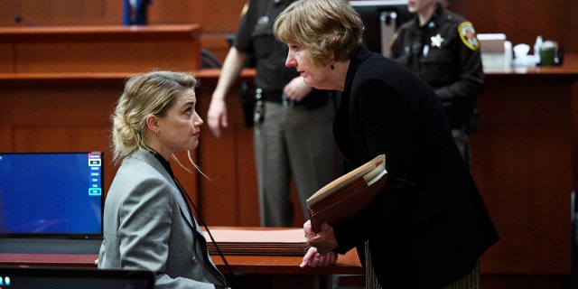 US actress Amber Heard speaks with her lawyer Elaine Bredehoft during the $50 million Depp vs Heard defamation trail at the Fairfax County Circuit Court April 12, 2022, in Fairfax, Virginia.